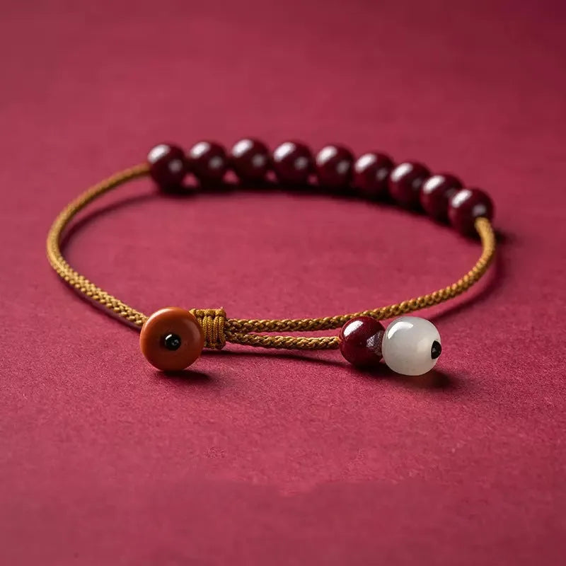 Close-up of a red cinnabar and beige Hetian jade geometric bracelet with a hand-woven adjustable strap.