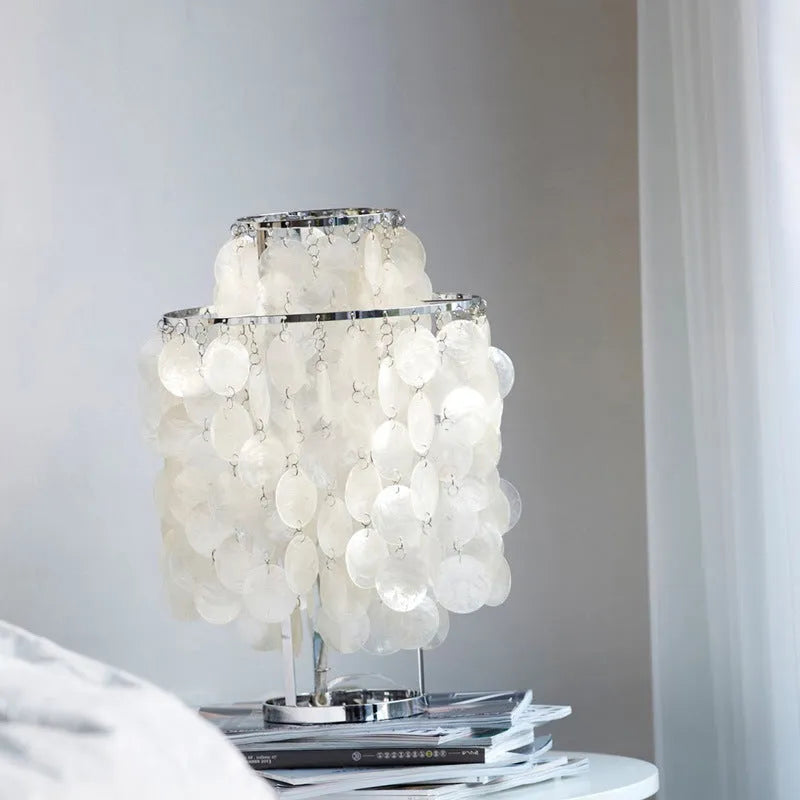 Modern single-head Shell bedside table lamp in chrome finish on a wooden table.
