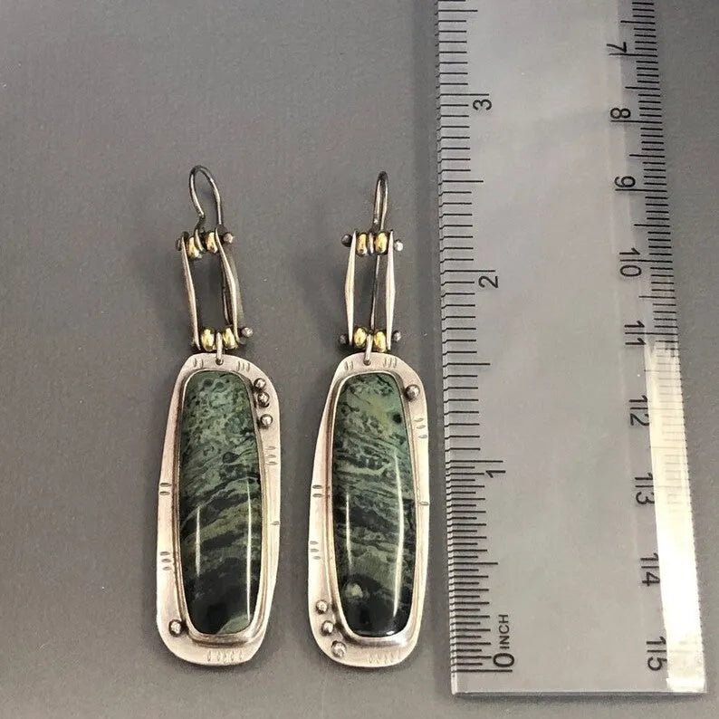 A pair of silver and grey geometric drop earrings with a marble stone pattern on a white background.