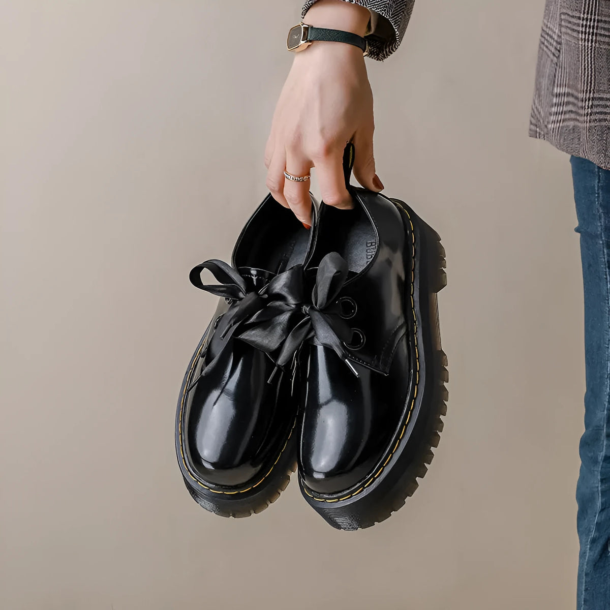 Black women's thick-soled leather lace-up shoes with a cross strap design on a white background.
