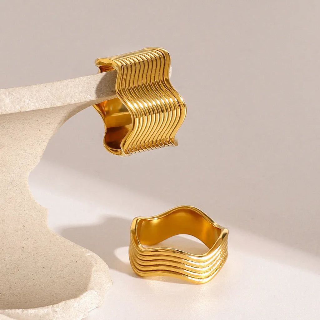Close-up of a stainless steel geometric wave ring with a wide, sculpted surface.