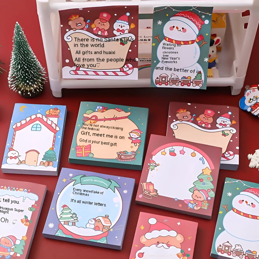Pad of cartoon Christmas sticky notes showing designs of an elf, gift box, sleigh, and Santa Claus.