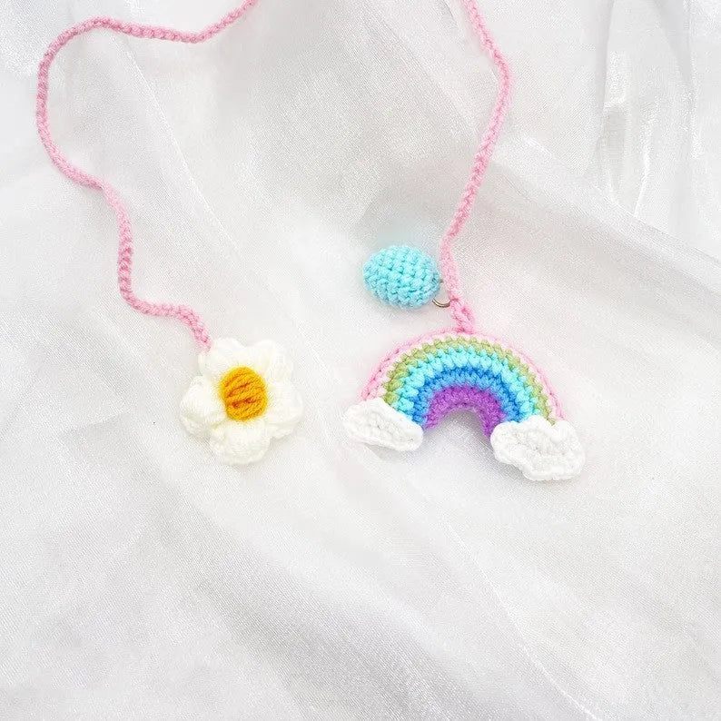 Handmade crocheted avocado-shaped car pendant with rainbow pattern, hanging.