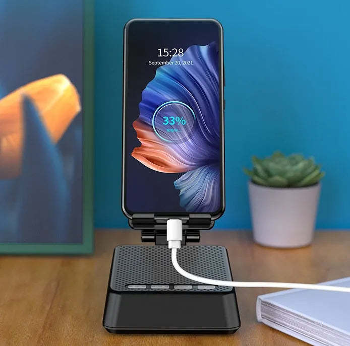 Black mobile phone broadcast stand with integrated Bluetooth speaker and microphone on a desk.
