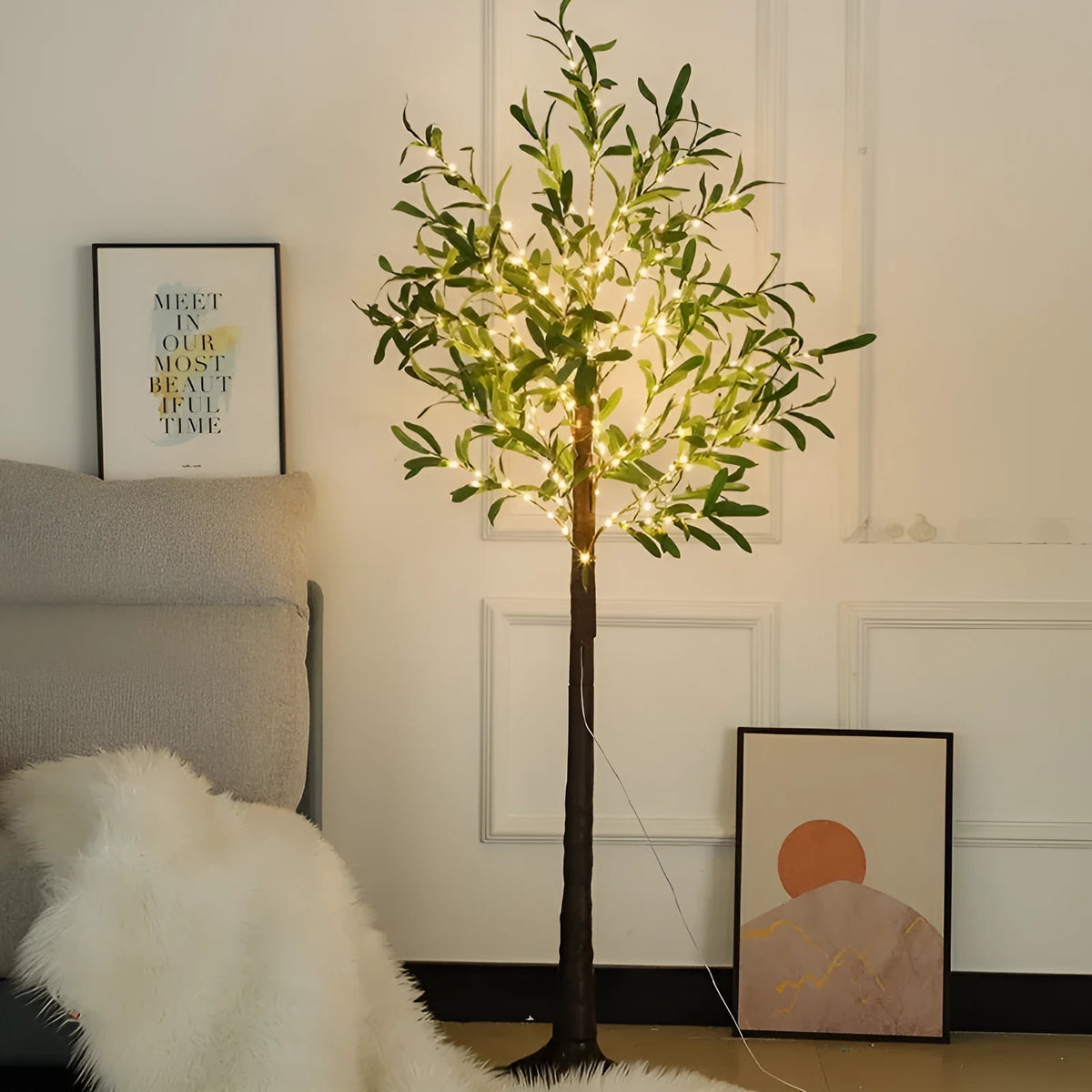 Tall artificial olive tree lamp with warm white LED lights illuminated in an outdoor courtyard setting.