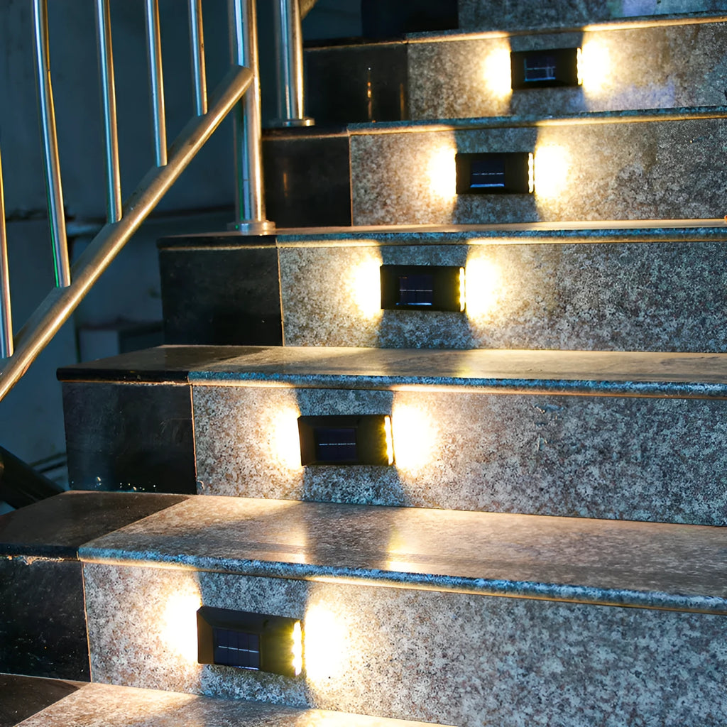 Solar-powered garden wall light mounted on outdoor brick wall illuminating pathway at night