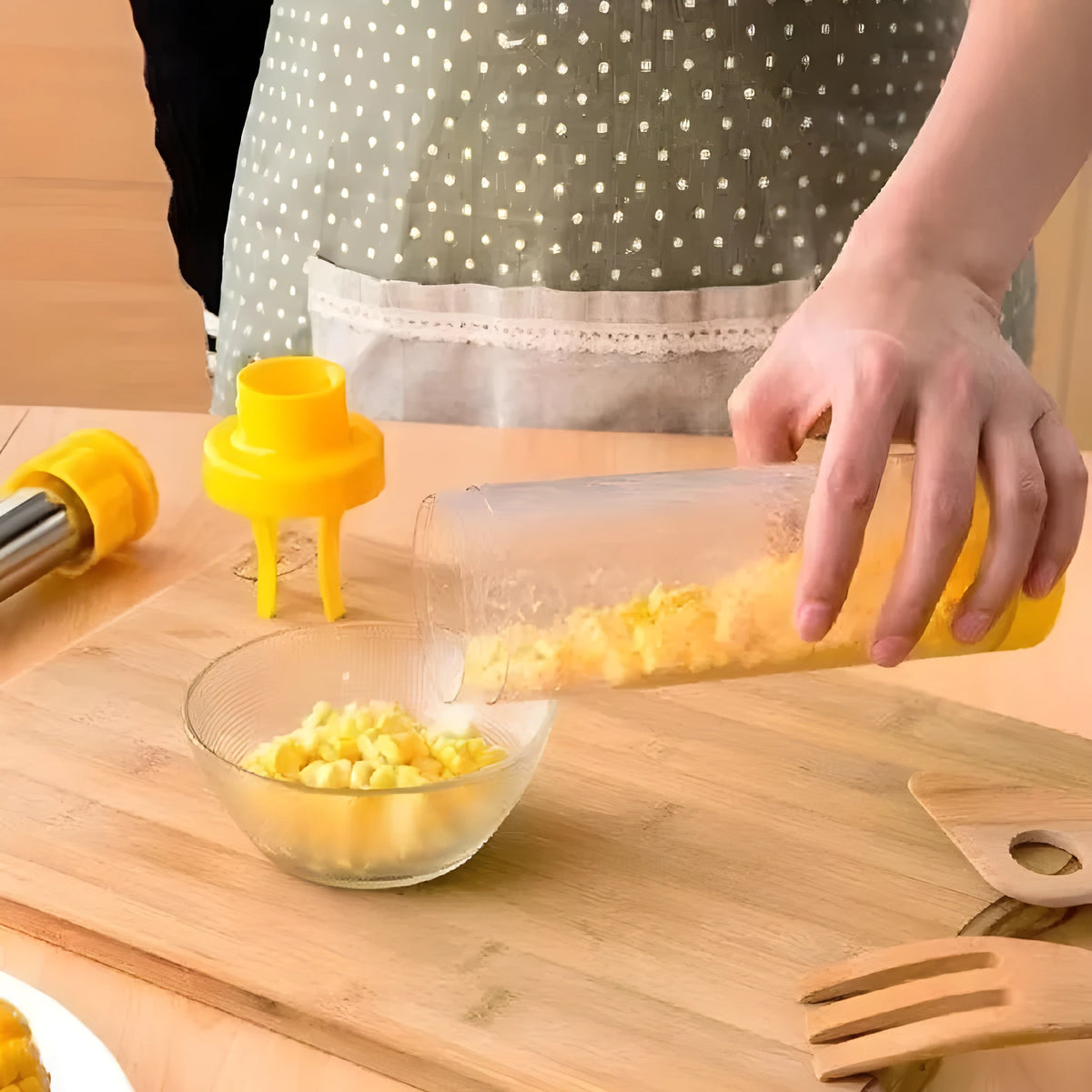 Yellow cylindrical corn stripper kitchen tool with stainless steel components on a kitchen worktop.