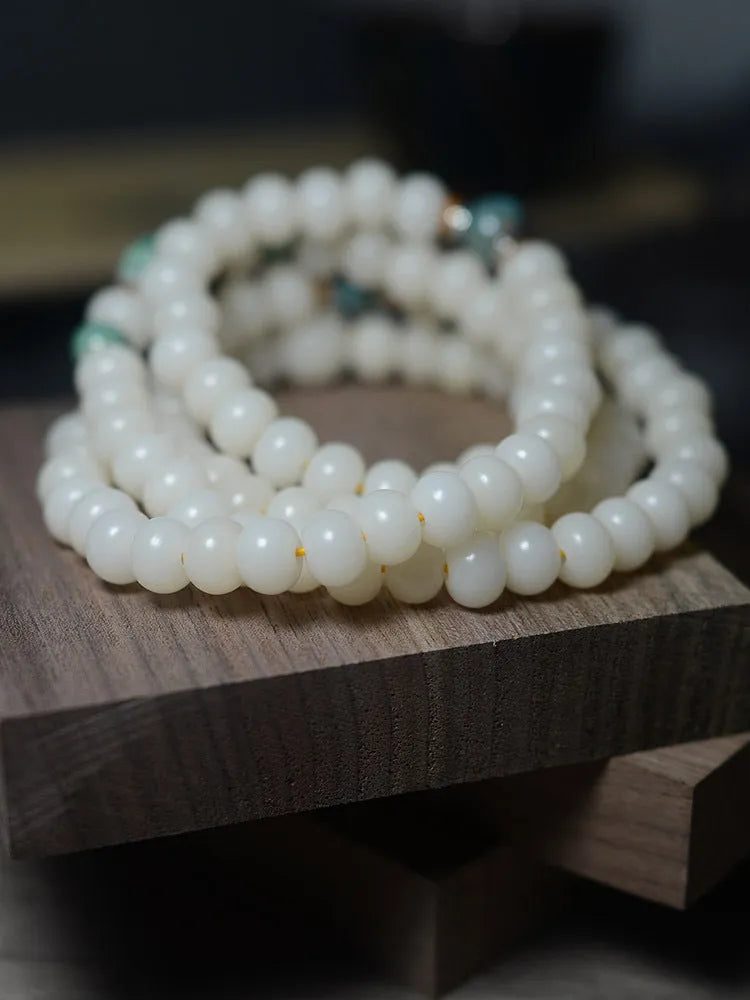 White jade bodhi root bracelet with 108 flat round beads in two sizes on a wrist.