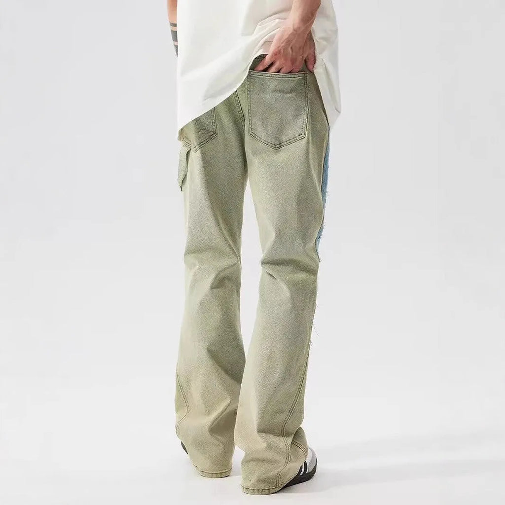 Yellow and blue patchwork jeans with a distressed splash-ink design on a mid-waist fit.