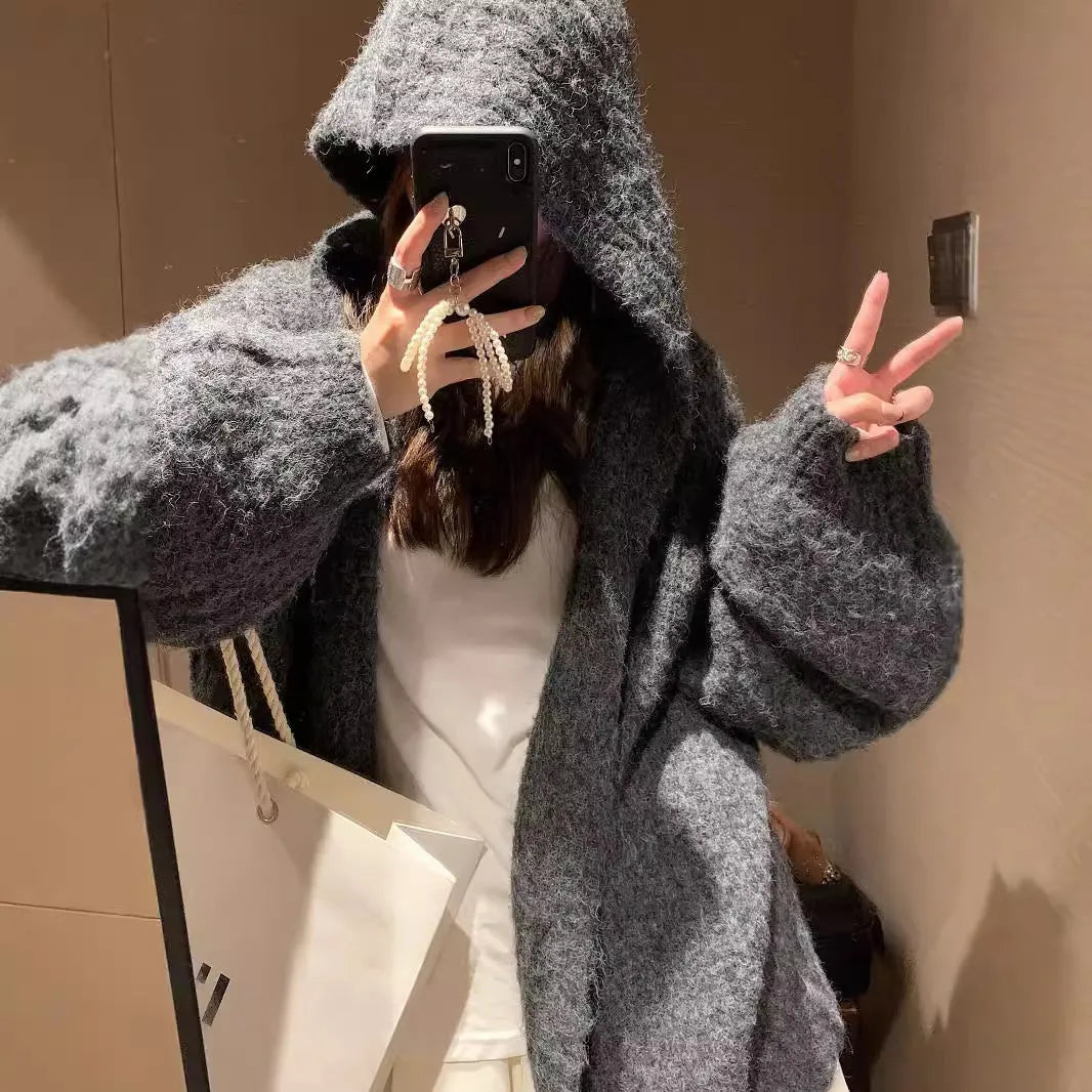 A woman wearing a thick, dark gray retro-style hooded cardigan with regular sleeves.