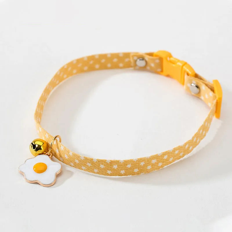 Green adjustable cat collar with a bow tie and bell pendant on a white background.