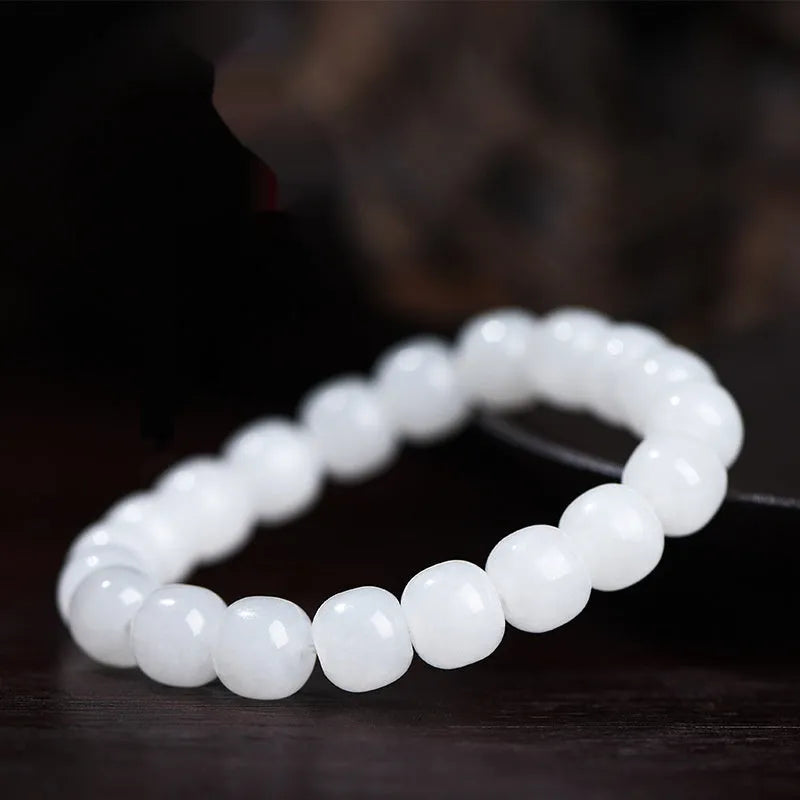 White Hetian jade barrel bead bracelet on a wrist, showing the smooth beads and casual unisex design.