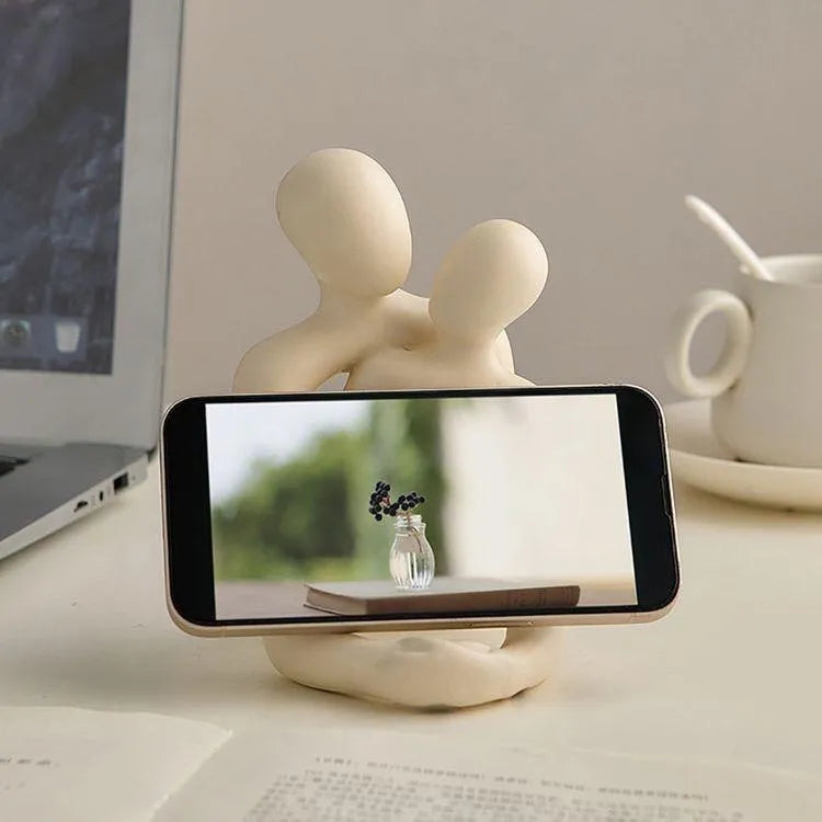 Modern heartwarming couple resin statue in milky white or gold colour on a wooden desk.