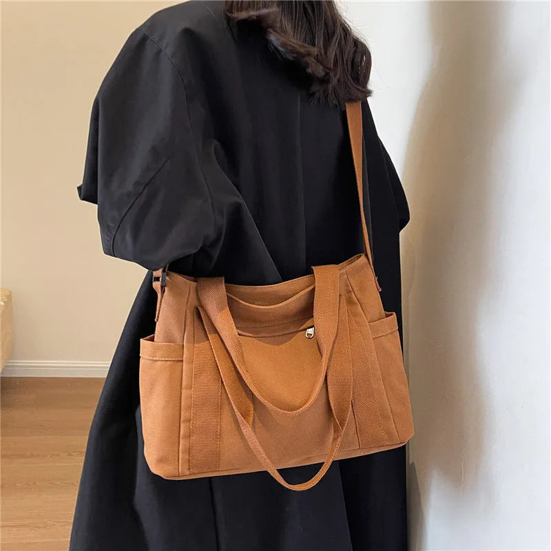 Women's solid colour canvas shoulder bag showing interior mobile phone compartment and exterior sandwich pocket
