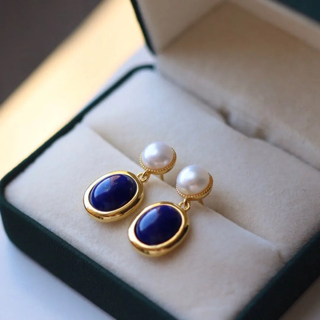 A pair of 925 sterling silver stud earrings with a deep blue lapis lazuli pearl and auspicious pattern details.