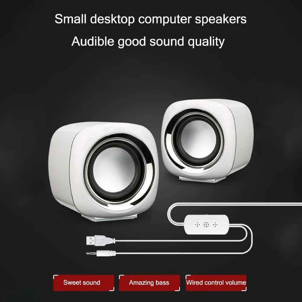 Compact black wired desktop computer speaker pair with 3.5mm plug next to a laptop.