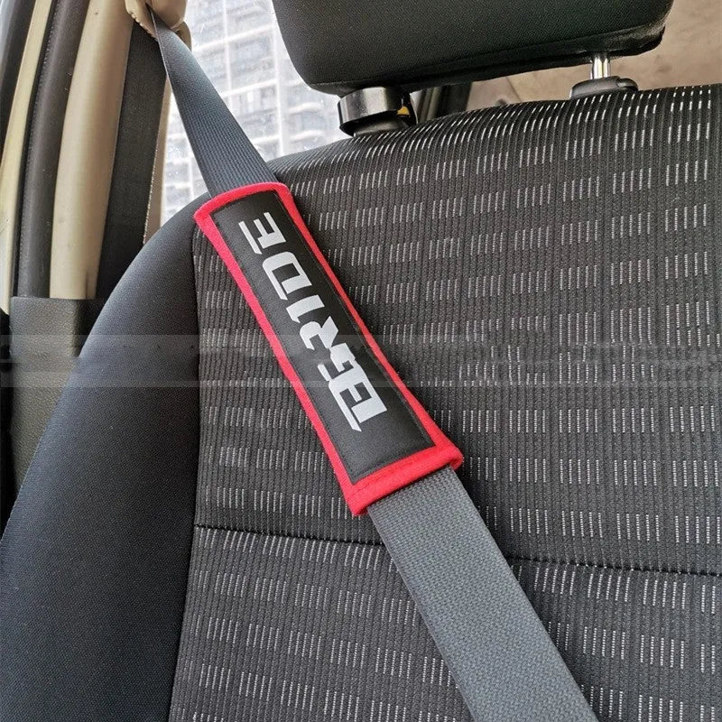 Pair of black cotton seatbelt shoulder pads with embroidery detail, showing dimensions