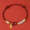 Women's adjustable silver bracelet with Hetian jade and red cinnabar rope decoration on a light background