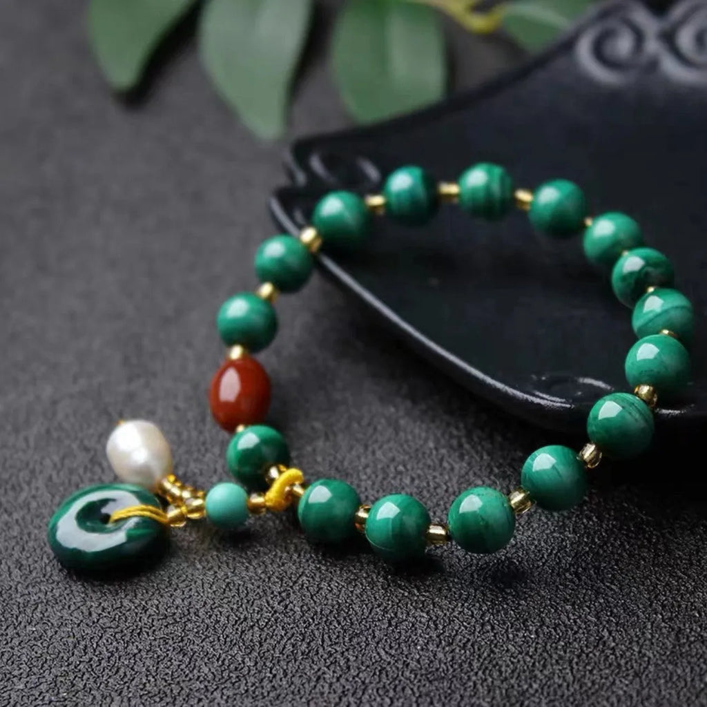 Handmade malachite and red agate bead bracelet with 7-8mm barrel beads on a wrist.