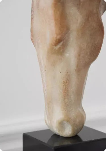 Tall abstract horse head sculpture with carved texture on a desk surface.