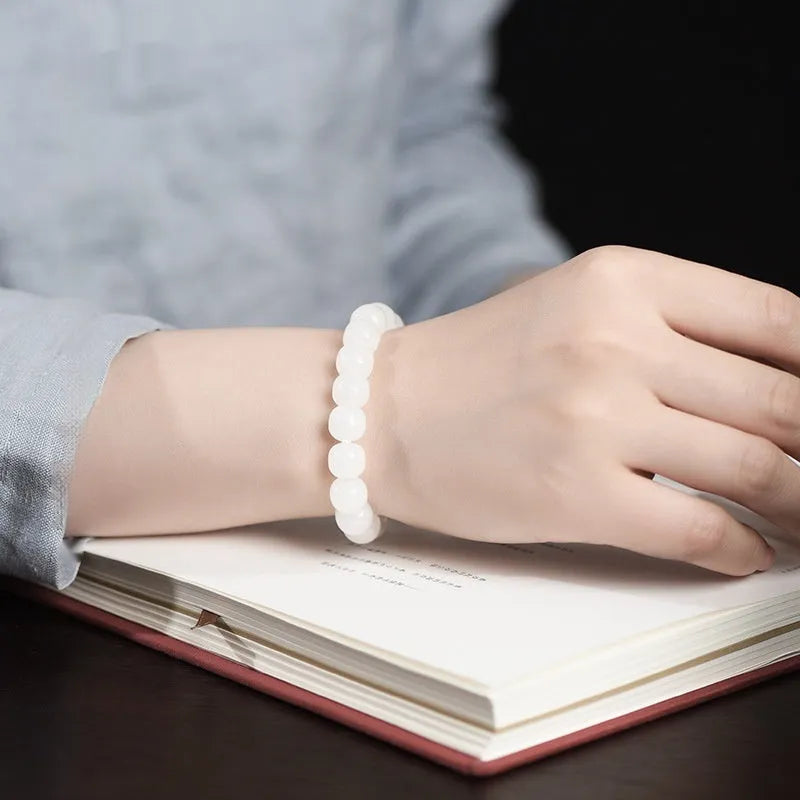 White Hetian jade barrel bead bracelet on a wrist, showing the smooth beads and casual unisex design.
