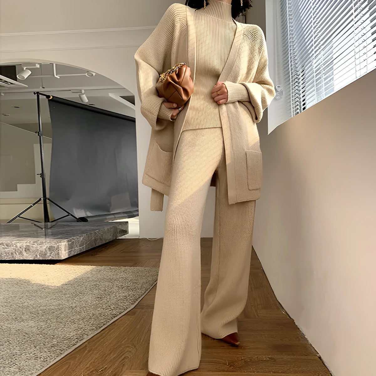 Women's apricot knitted three-piece set showing top, wide-leg pants, and cardigan coat with leather stitching detail.