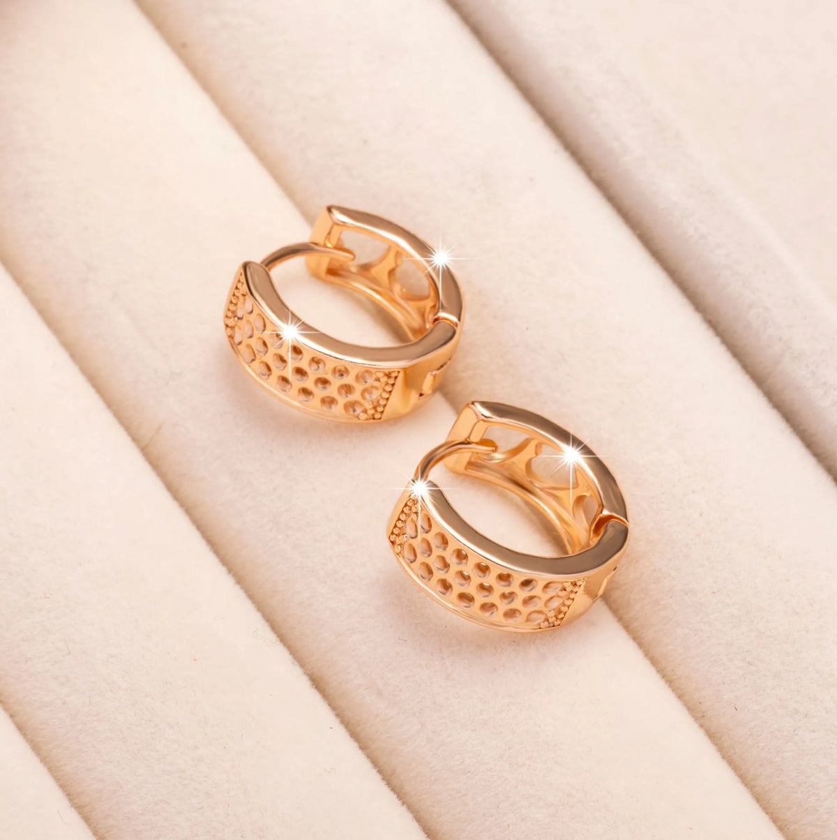 Rose gold electroplated drop earrings with three hollowed-out hearts in a circular arrangement.