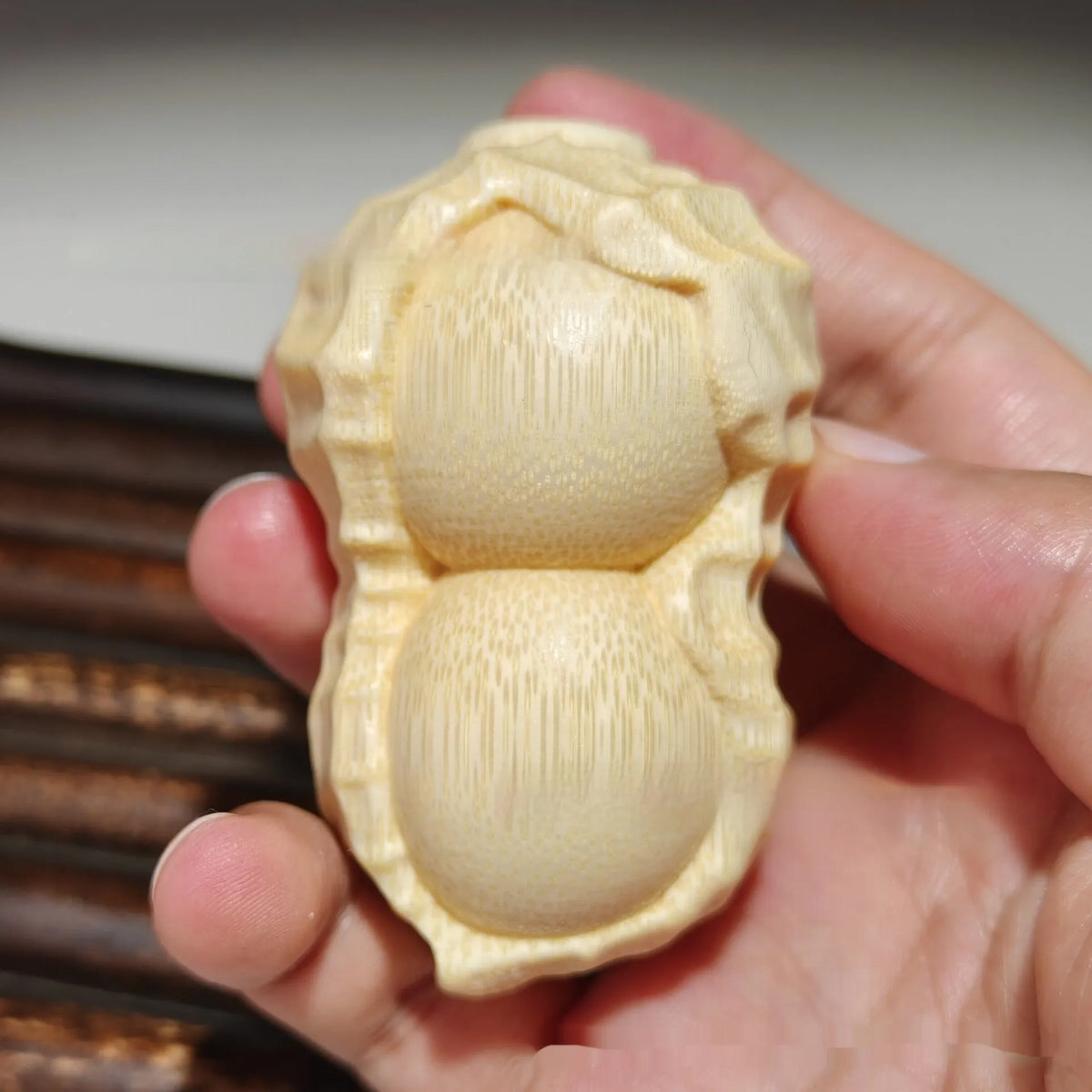 Solid natural bamboo carving peanut ornament on a neutral background