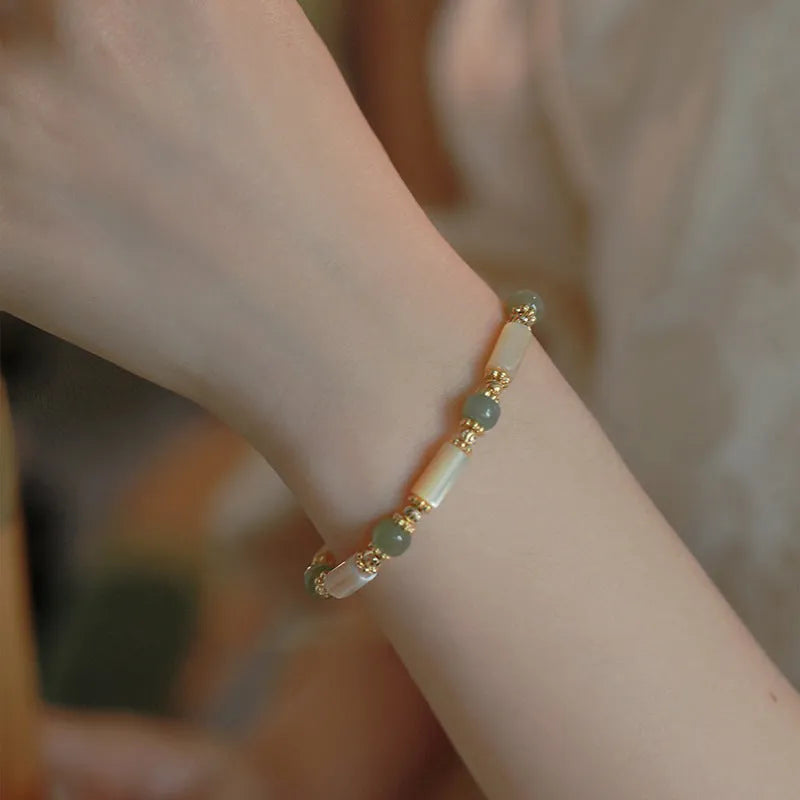 A women's adjustable bracelet made of round white Hetian jade beads in a simple geometric design.
