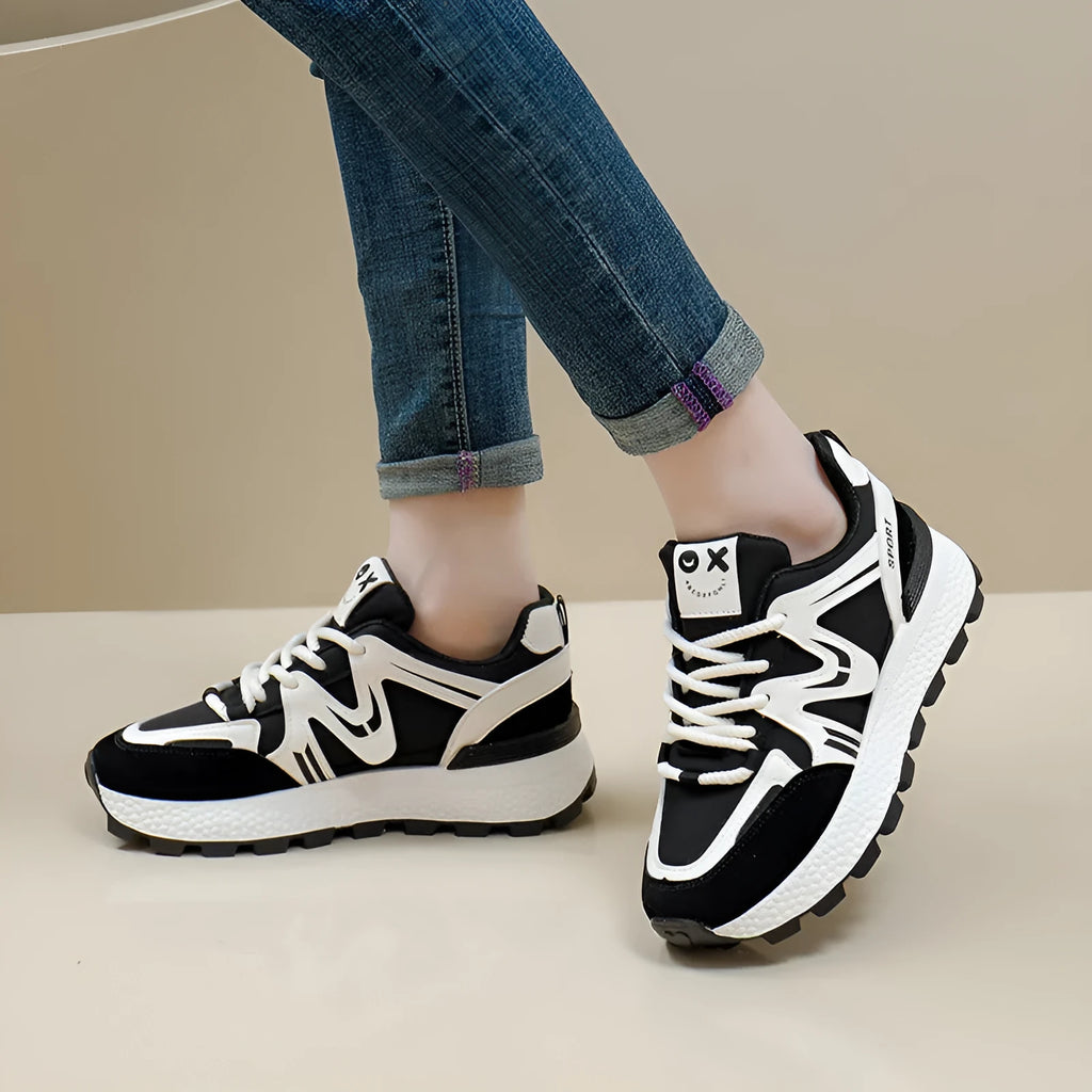 Women's black platform casual sports shoes with flat heel and white lace-up front closure on a neutral background.