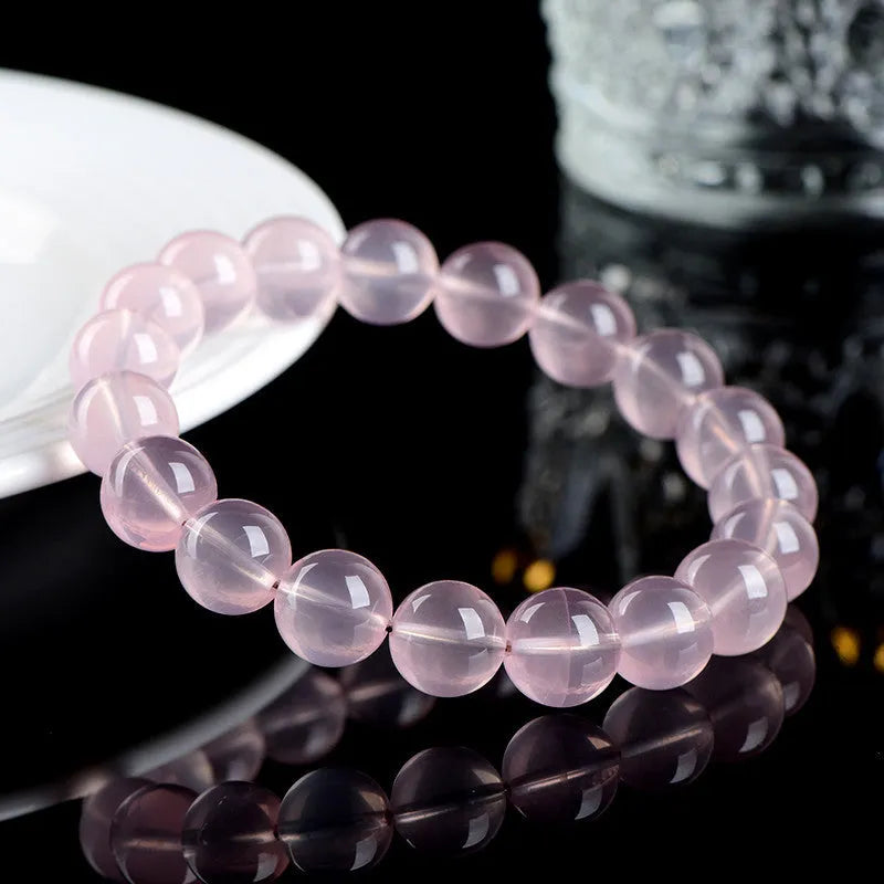 Close-up of a women's bracelet with polished round pink crystal beads on a single strand, showing smooth surface and sparkle.