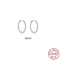 Close-up of a pair of twisted string round sterling silver ring earrings on a flat surface.