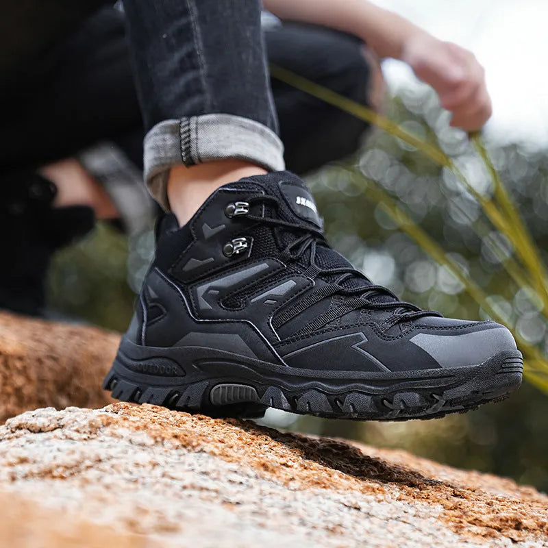 Hiking sneaker with flannel upper and rubber sole in black, shown on a rocky outdoor path.
