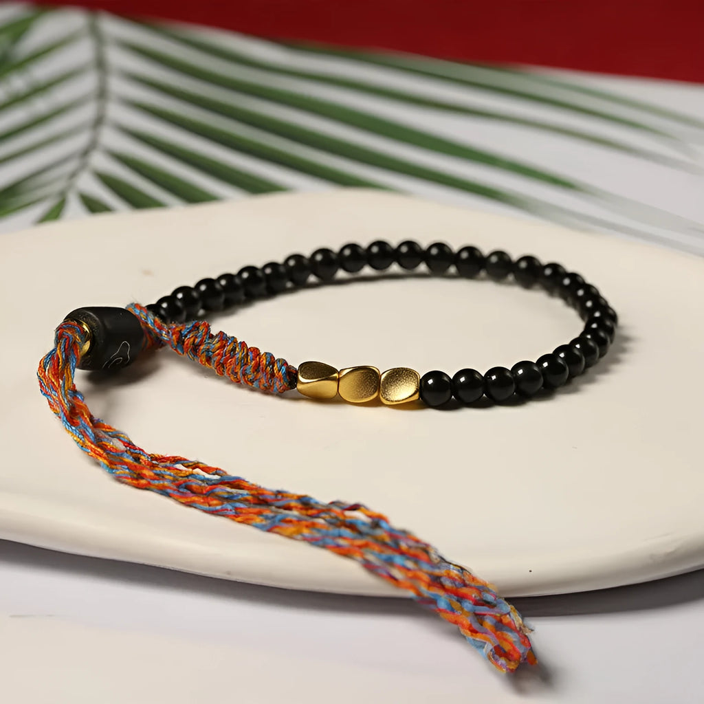 Slim obsidian-coloured hand-woven strap bracelet shown on a wrist.