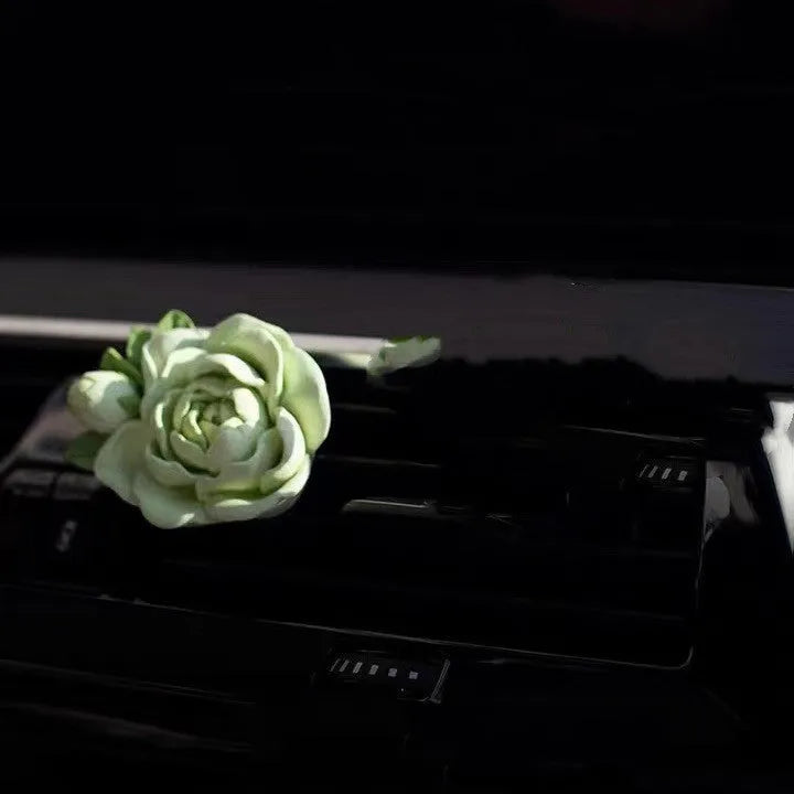 Jasmine car perfume solid air freshener in vent with gypsum base and essential oil bottle.