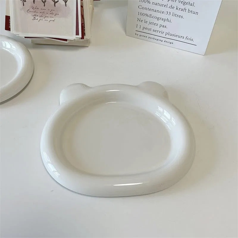 White porcelain plate with chubby toot design, showing bear or round doodle pattern, on a table.