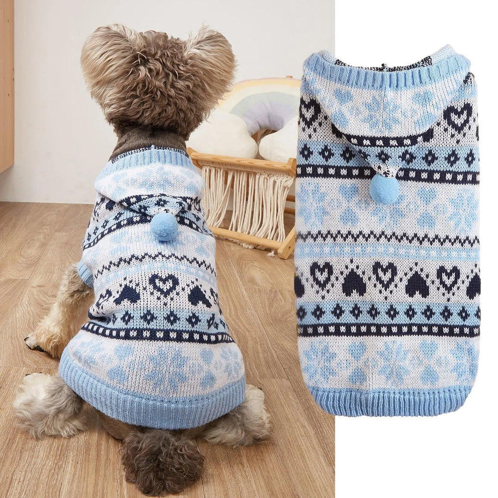 Pink knitted dog sweater with snowflake, heart, and camouflage stripe pattern on a small white dog.