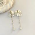 Women's acrylic fashion earrings with white shell and pearl tassel design on a silver-toned ear clip.