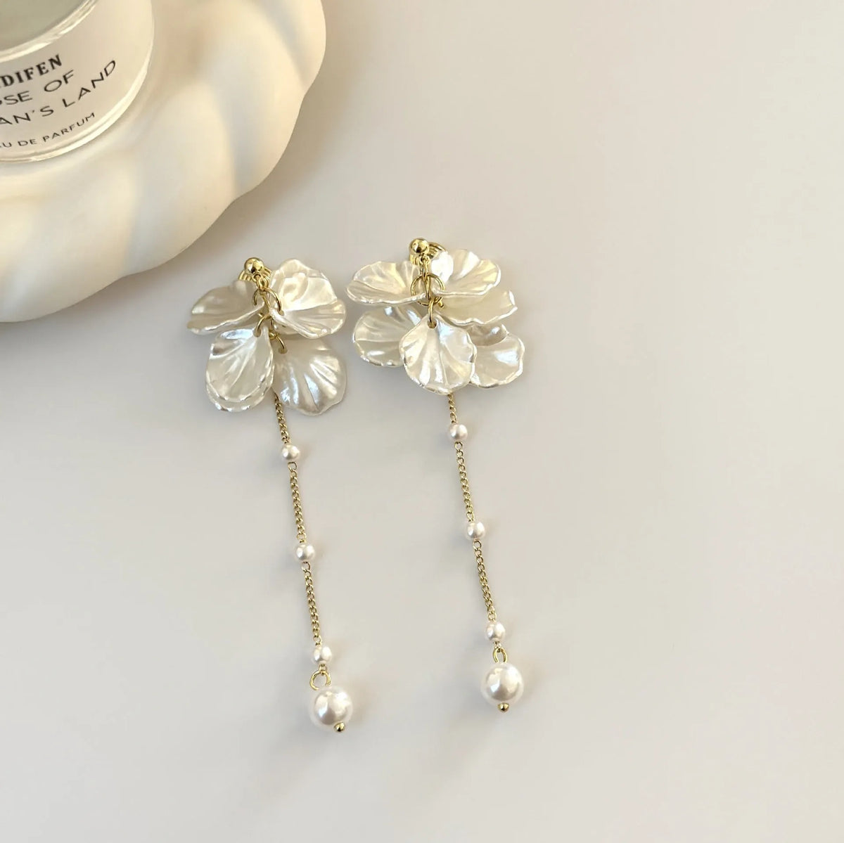 Women's acrylic fashion earrings with white shell and pearl tassel design on a silver-toned ear clip.