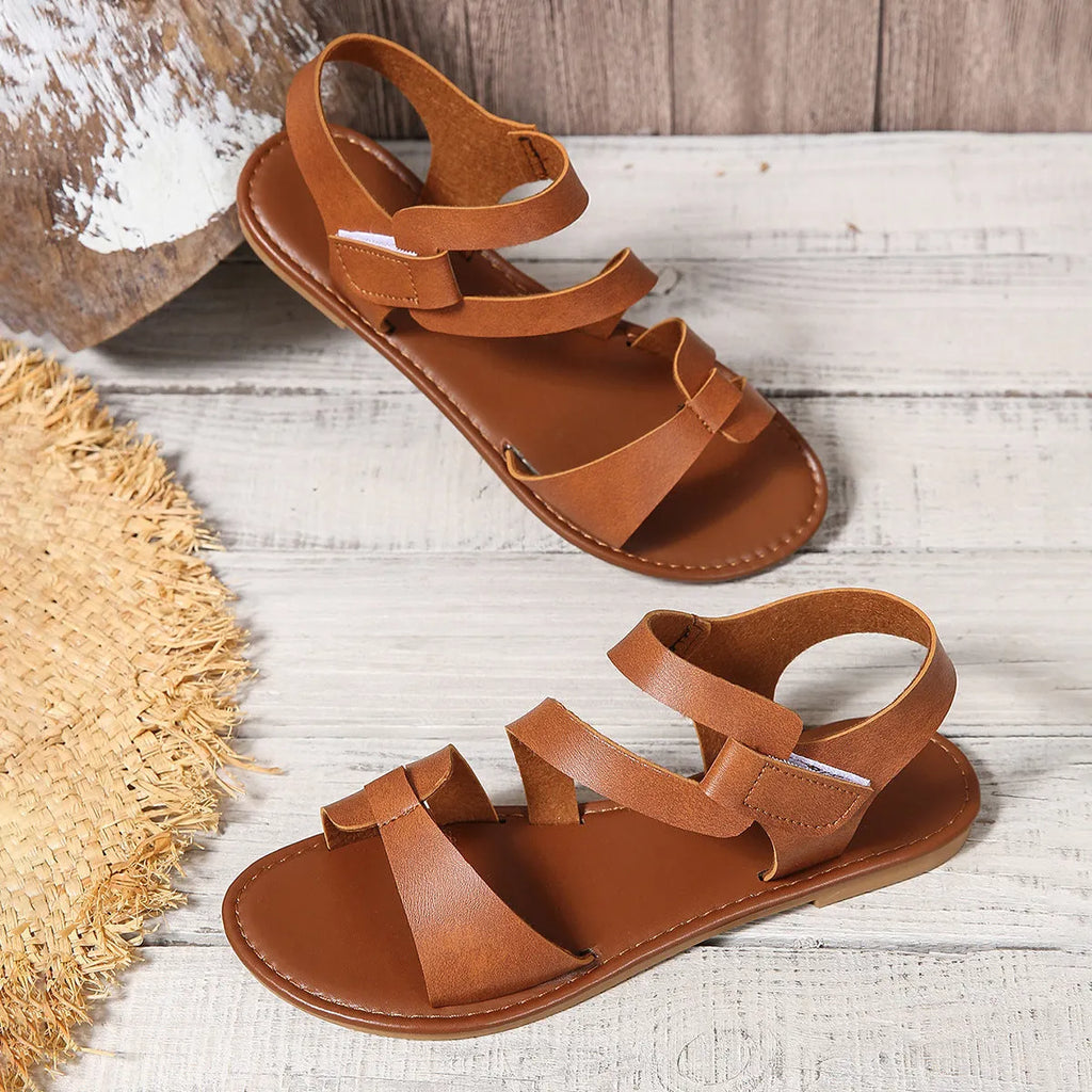 Women's flat sandals with Velcro strap, round toe, and a brown PU upper on a rubber sole.