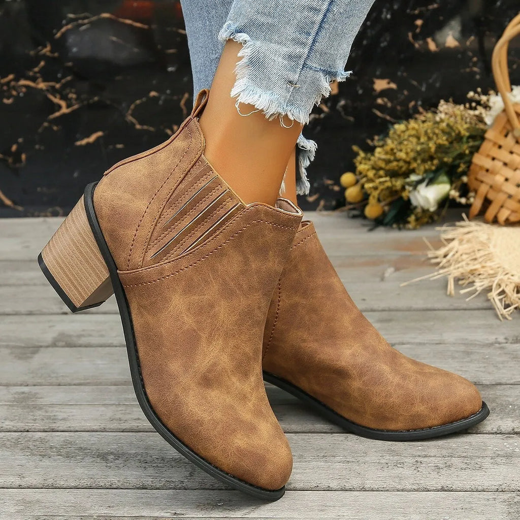 Women's black ankle boots with pointed toes and thick square heels on a solid background