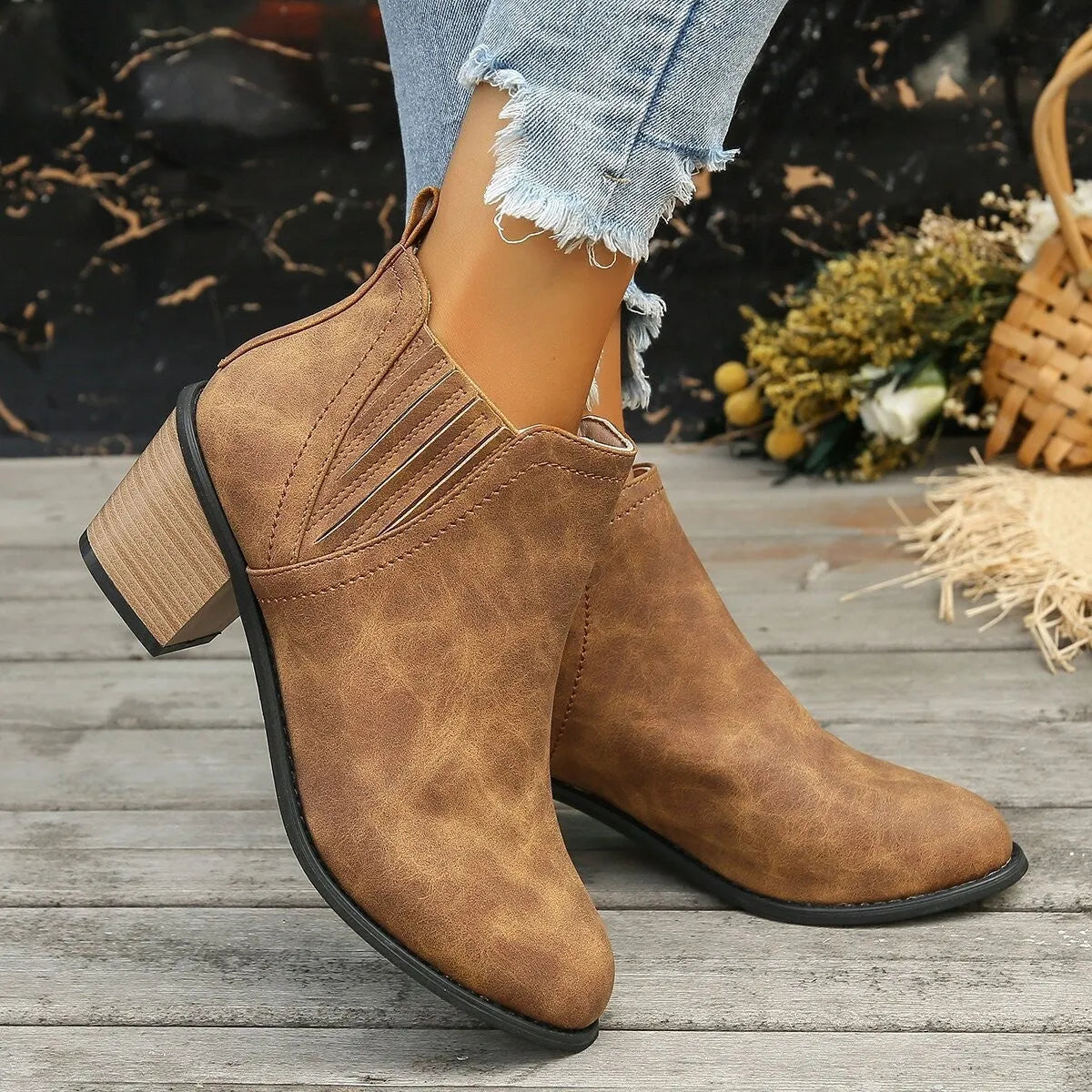 Women's black ankle boots with pointed toes and thick square heels on a solid background