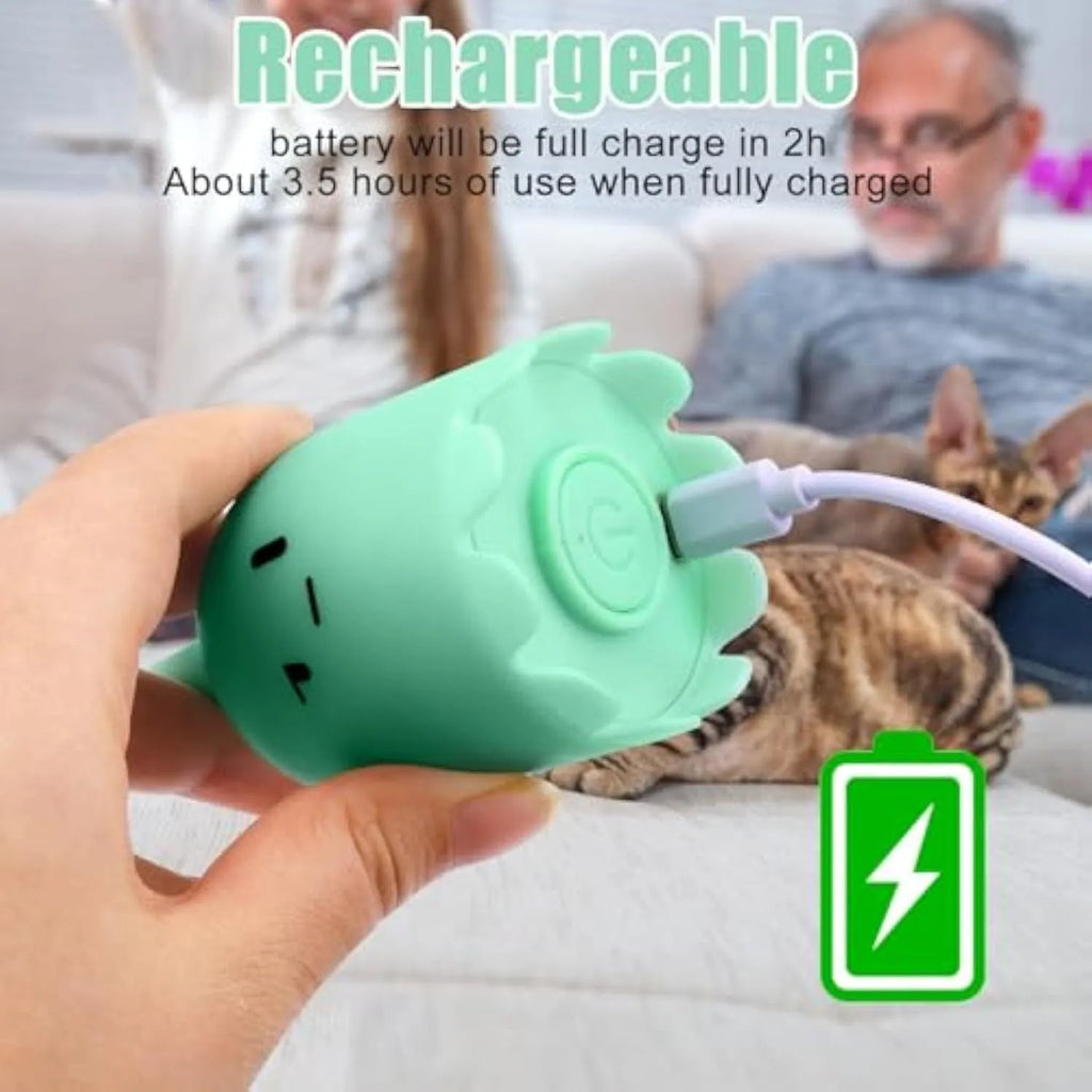 Green automatic cat toy with swinging silicone tails on a wooden floor.
