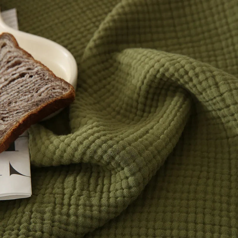 Four-layer cotton gauze tassel blanket in avocado green colour showing tassel detailing