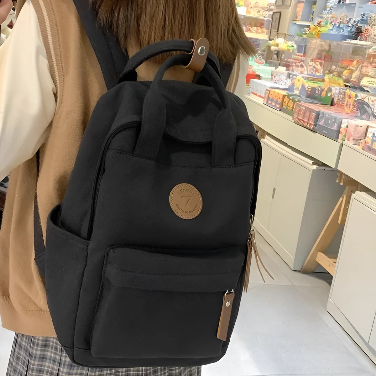 Solid black Oxford cloth leisure backpack with curved shoulder straps and retro styling details