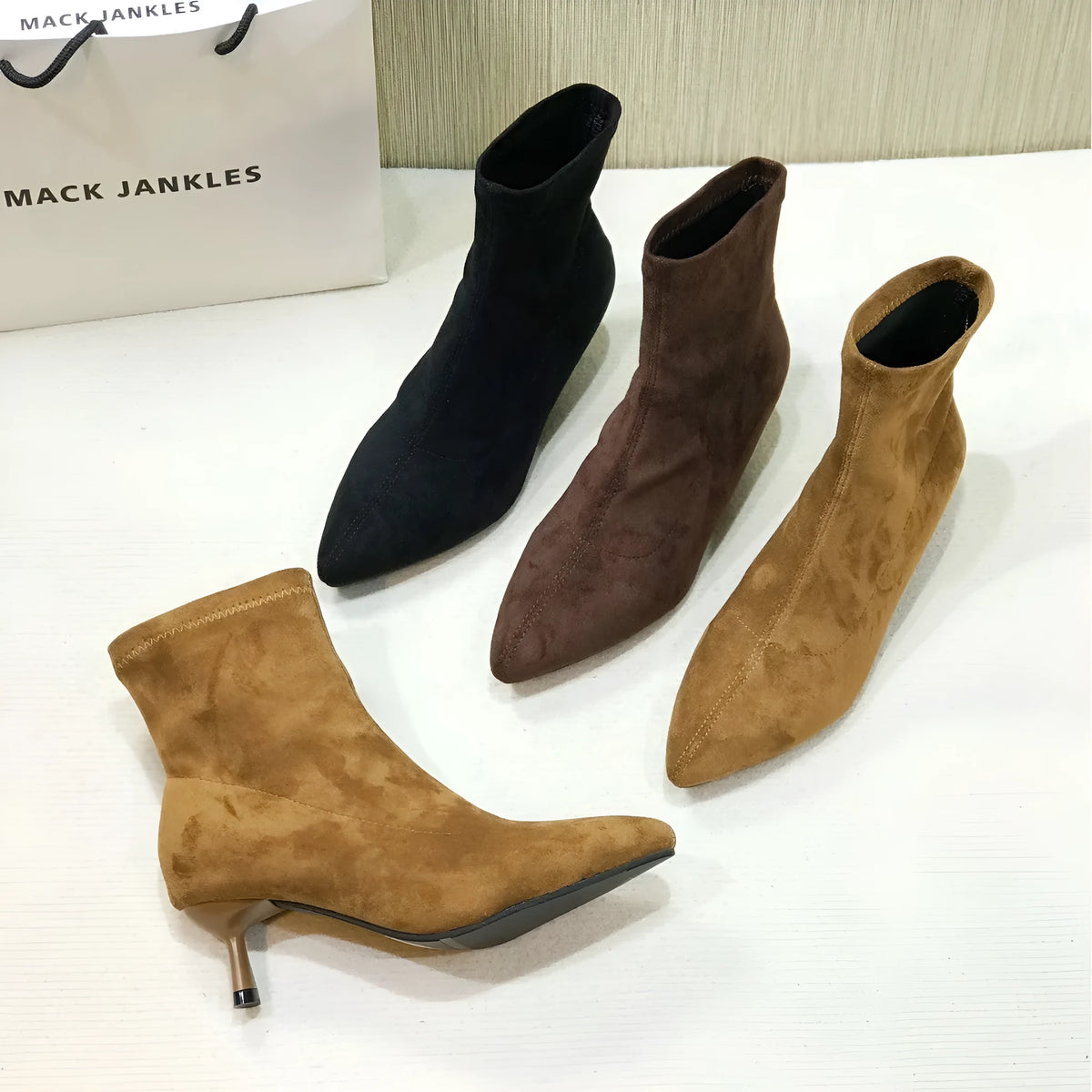 Women's black pointed toe ankle boots with a stiletto heel on a white background.