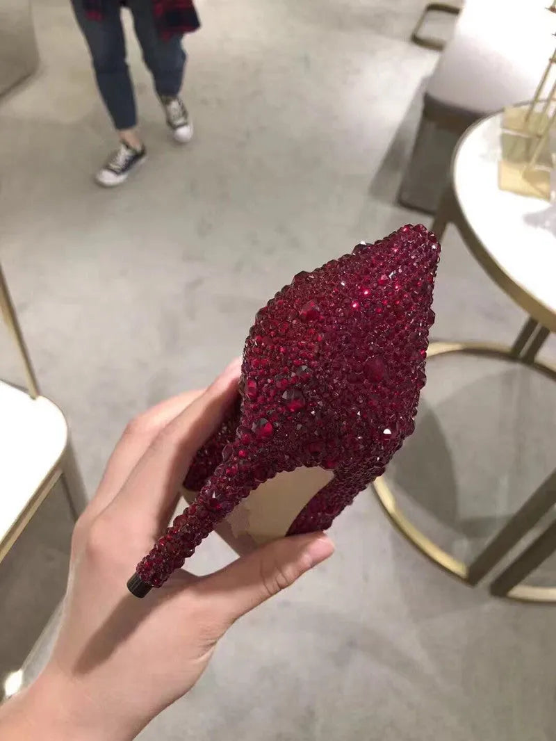 Women's gold stiletto high heels with rhinestone and bow decorations on pointed toe.