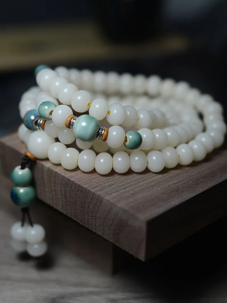 White jade bodhi root bracelet with 108 flat round beads in two sizes on a wrist.
