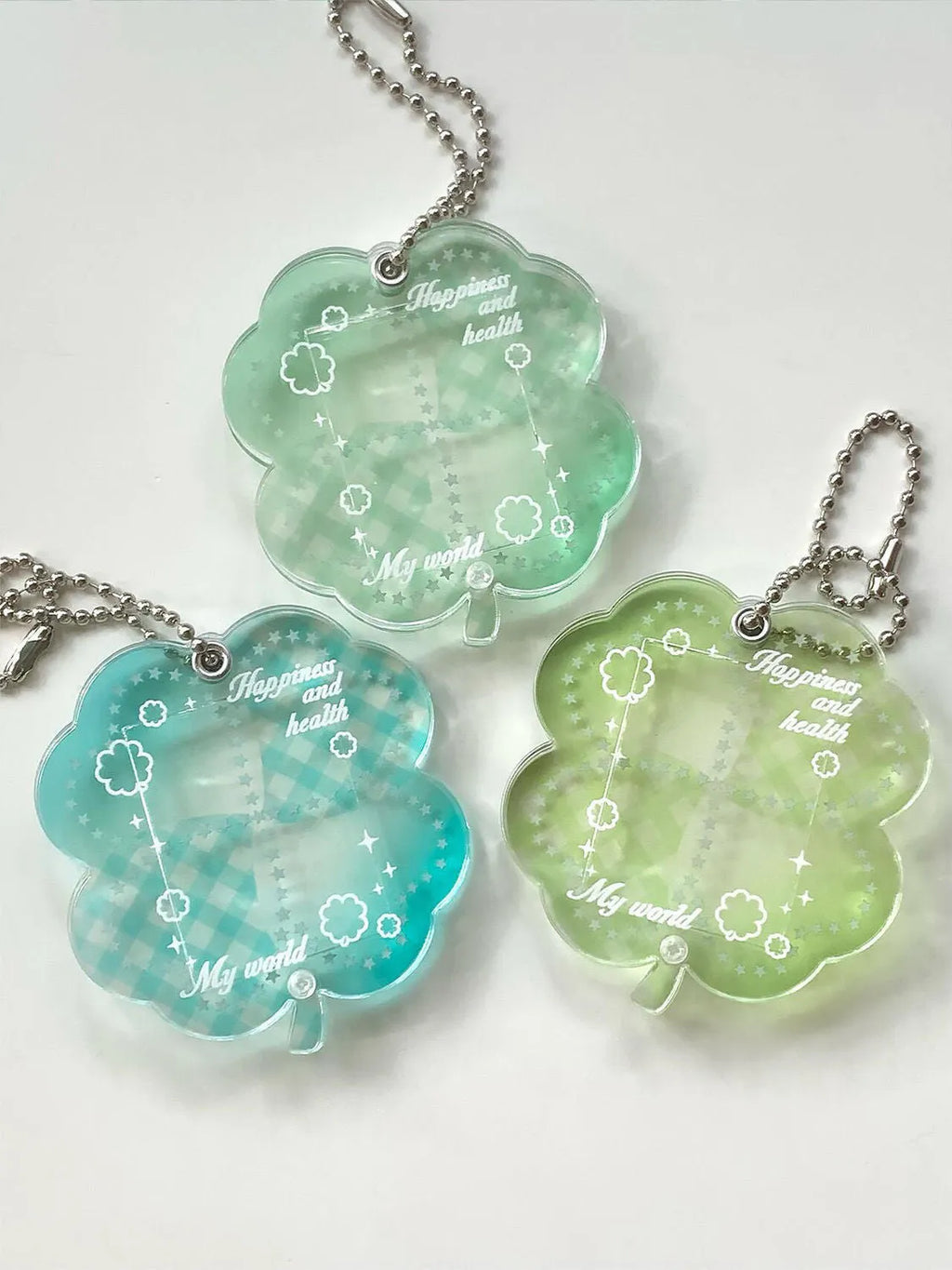 Four-leaf clover shaped acrylic phone pendant keychain in blue, green, and mint colour variations