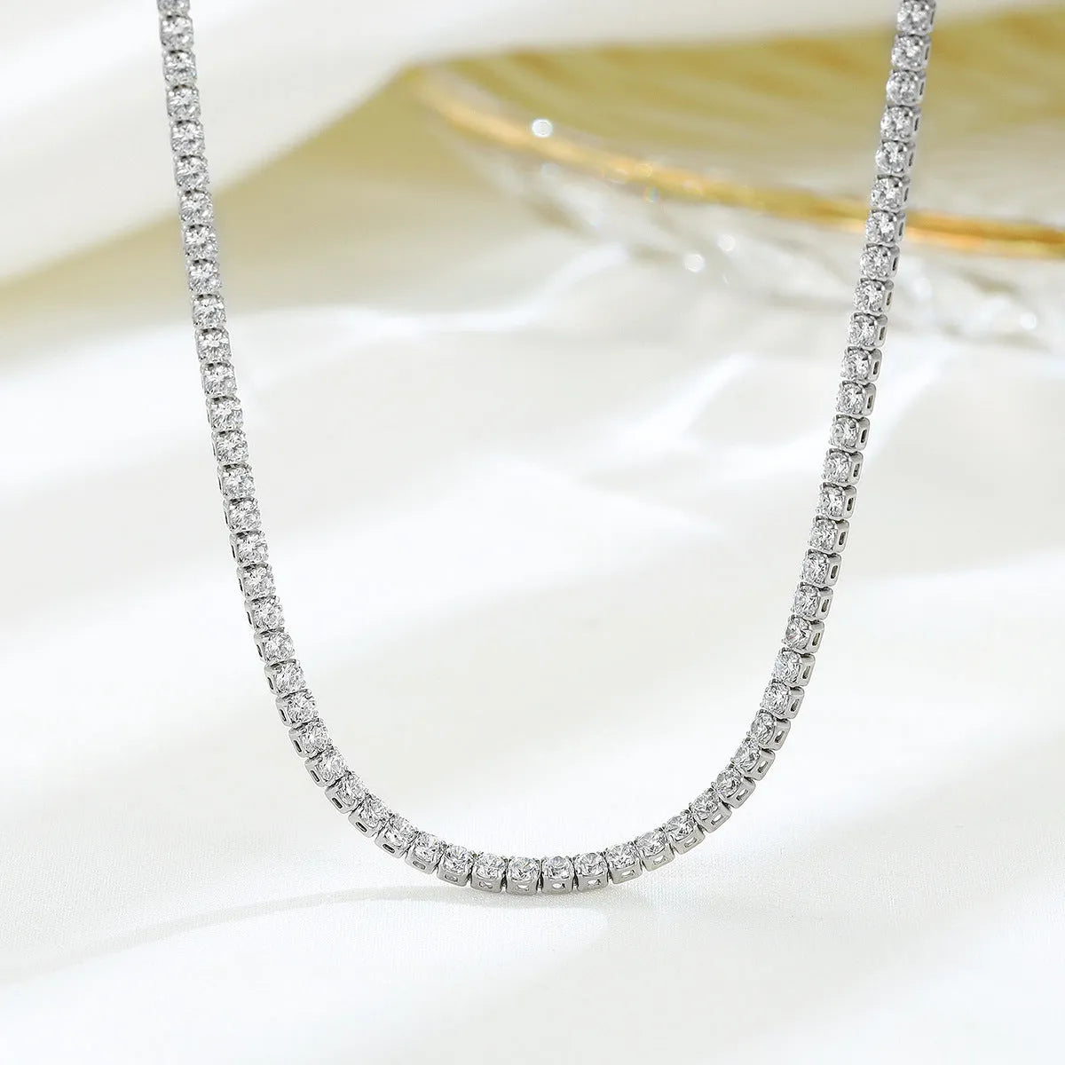 Close-up of a women's sterling silver necklace with round diamond-cut elements on a polished chain.